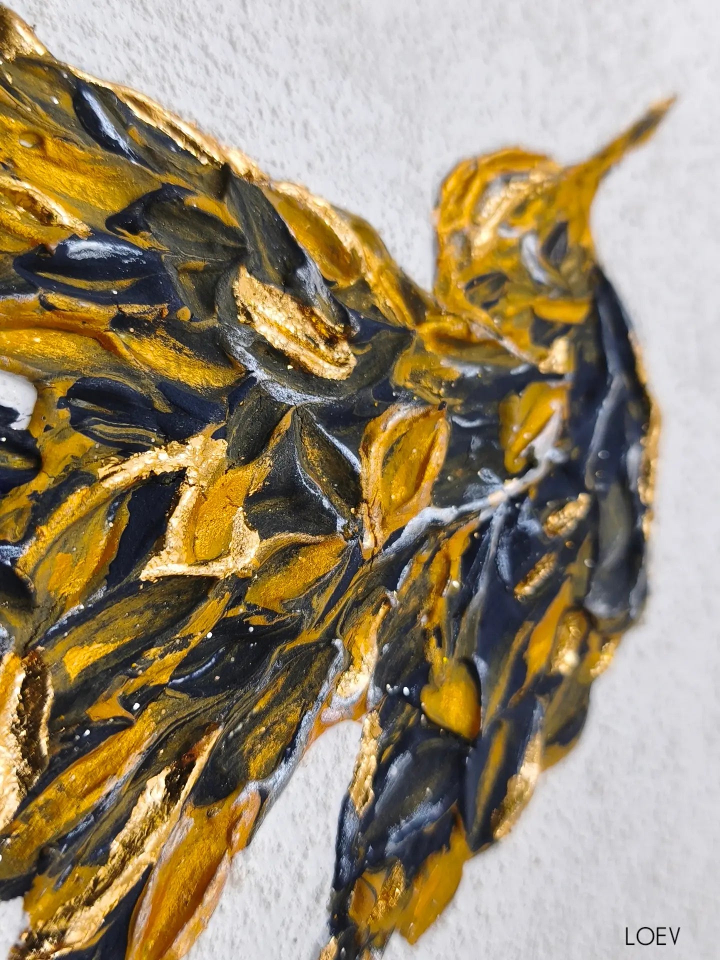 Gros plan sur l’aile du colibri texturé avec détails bleu profond, reliefs épais et reflets dorés lumineux