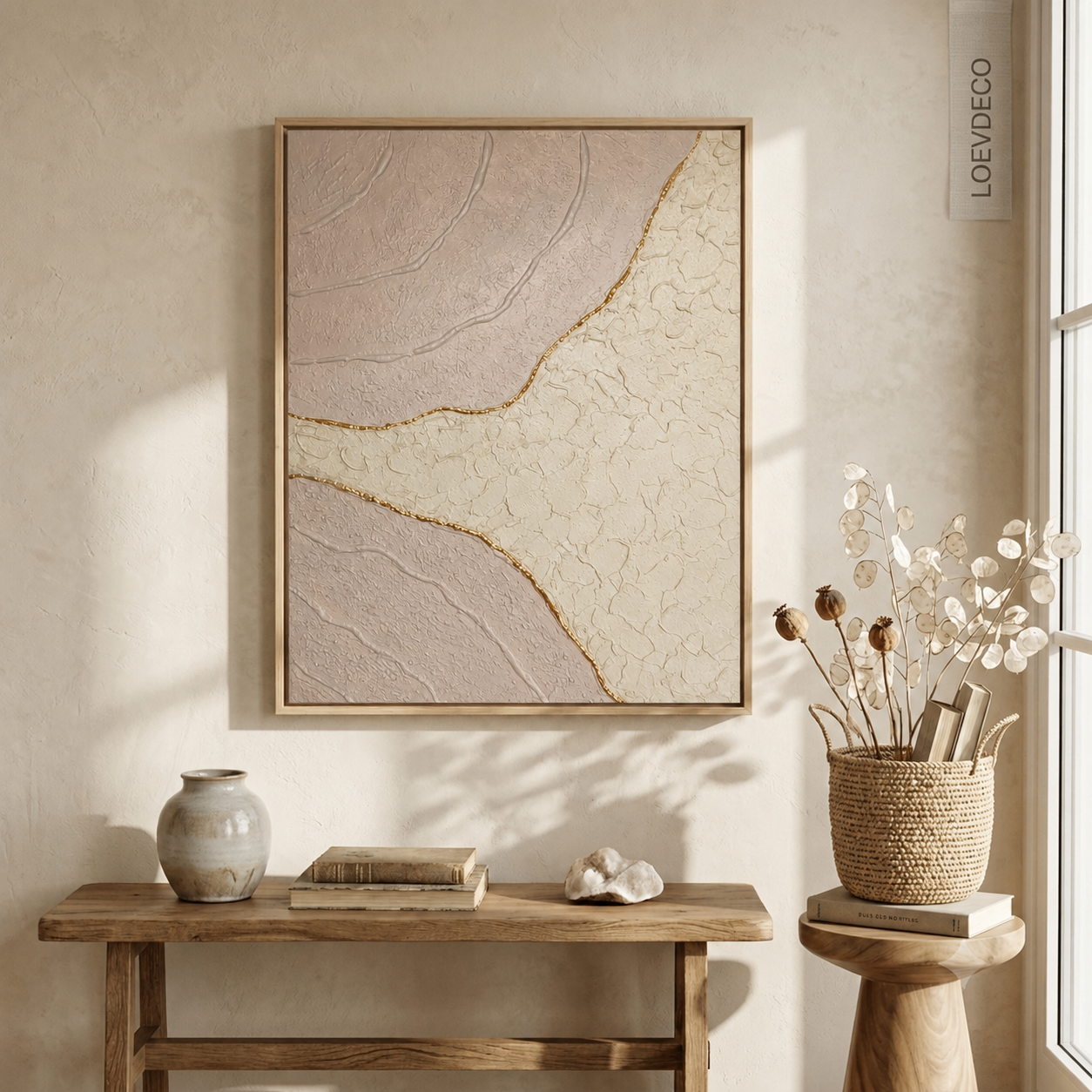 Gros plan sur une œuvre d'art faite main, montrant la texture en relief dans des tons crème et rose poudré avec une séparation délicate en feuille d'or
